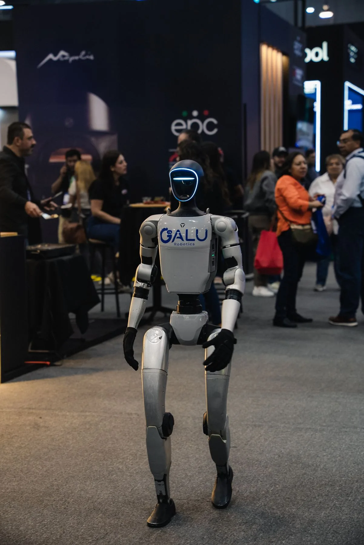 Robot humanoide Galu caminando en un piso de expo, rodeado de asistentes.